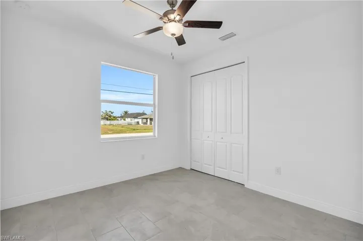 Unfurnished bedroom with ceiling fan and a closet
