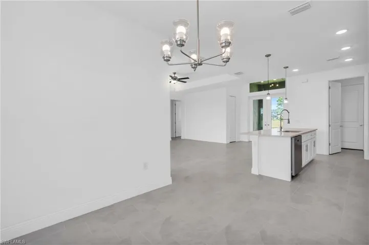Kitchen featuring ceiling fan with notable chandelier, sink, pendant lighting, dishwasher, and an island with sink
