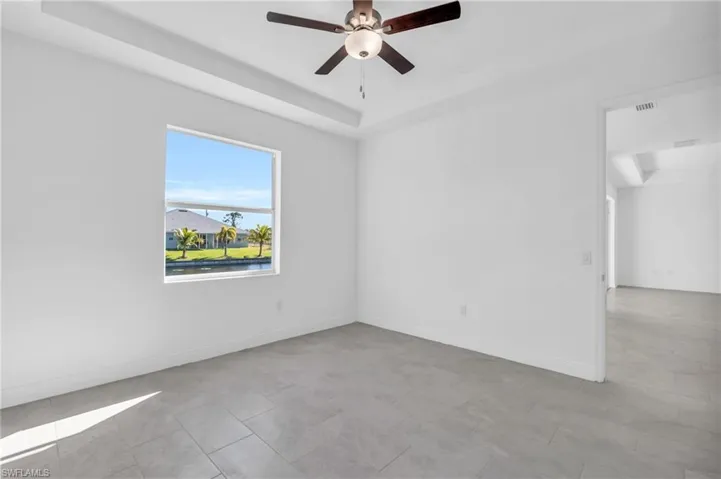 Tiled spare room featuring a raised ceiling and ceiling fan