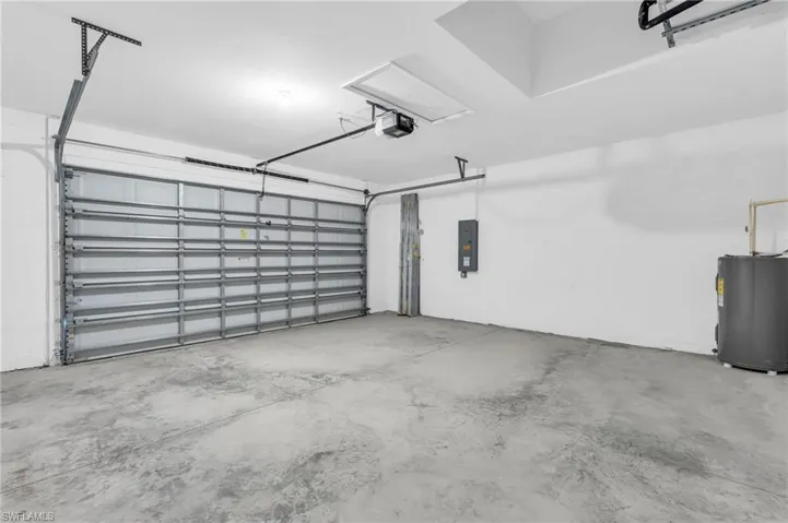 Garage with electric panel, a garage door opener, and water heater