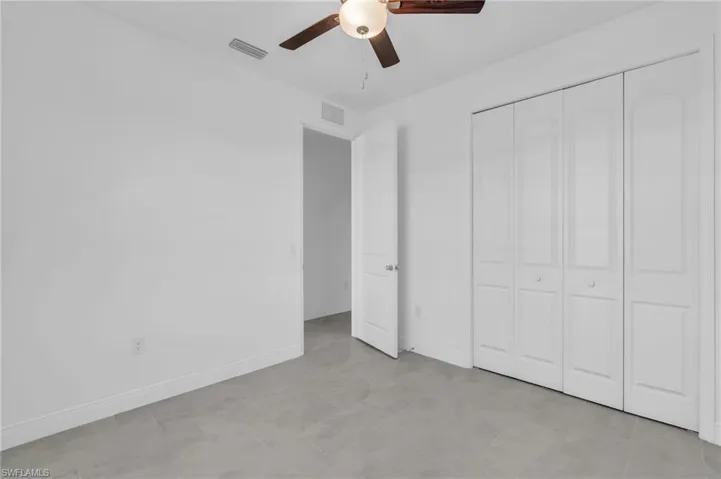 Unfurnished bedroom with ceiling fan and a closet