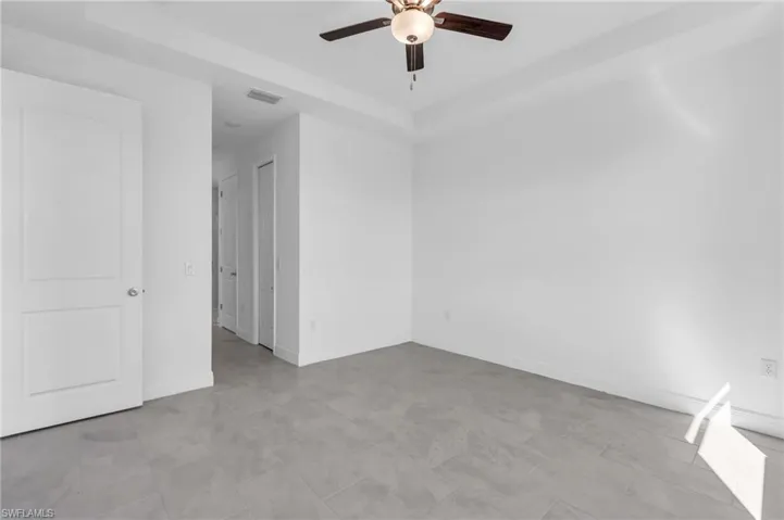 Unfurnished room featuring ceiling fan, a raised ceiling, and light tile patterned floors