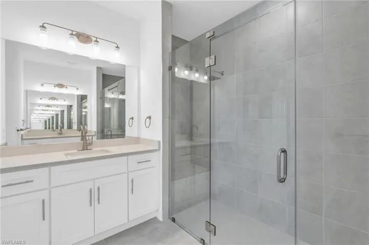 Bathroom featuring tile patterned floors, vanity, and a shower with shower door