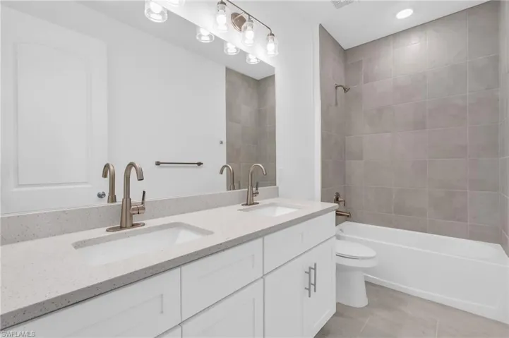 Full bathroom featuring tile patterned floors, vanity, toilet, and tiled shower / bath