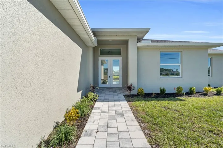 View of exterior entry featuring french doors and a yard
