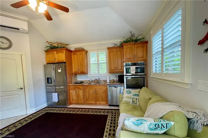 Kitchen with light tile patterned floors, stainless steel appliances, vaulted ceiling, and ceiling fan