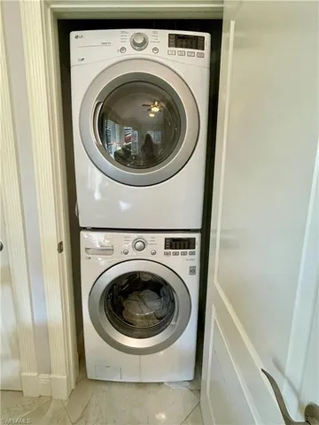 Laundry room featuring light tile patterned floors and stacked washer / drying machine