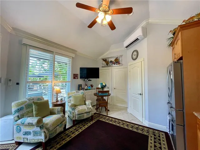 Tiled living room with ceiling fan, crown molding, an AC wall unit, and lofted ceiling