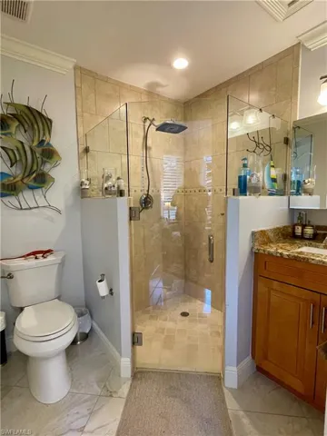Bathroom featuring crown molding, toilet, an enclosed shower, tile patterned floors, and vanity