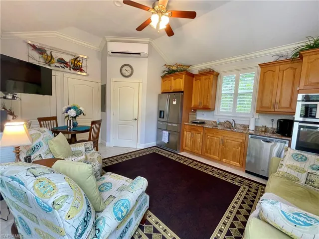 Kitchen featuring light tile patterned floors, appliances with stainless steel finishes, ornamental molding, ceiling fan, and vaulted ceiling
