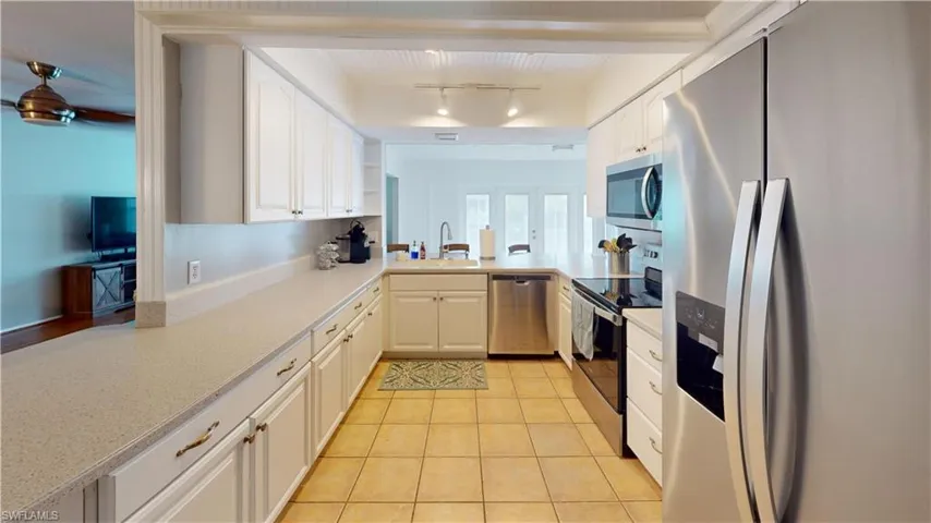 Kitchen with ceiling fan, rail lighting, appliances with stainless steel finishes, sink, and light tile floors