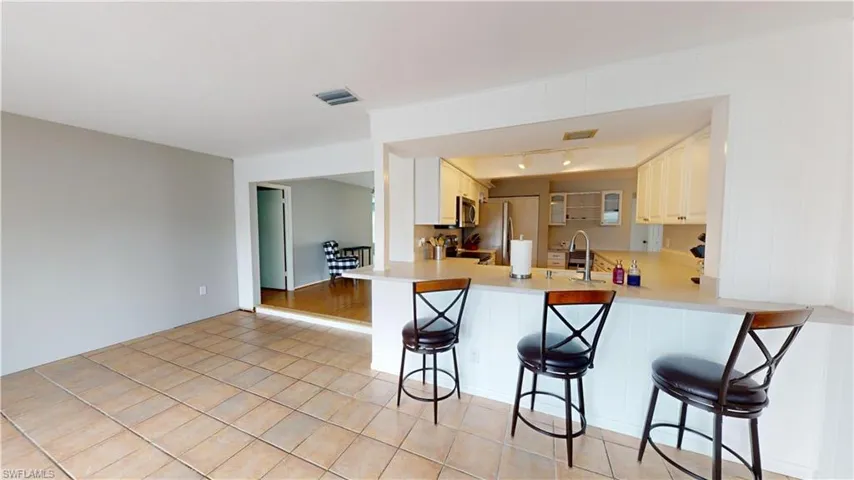 Kitchen featuring kitchen peninsula, light tile floors, sink, a kitchen bar, and appliances with stainless steel finishes