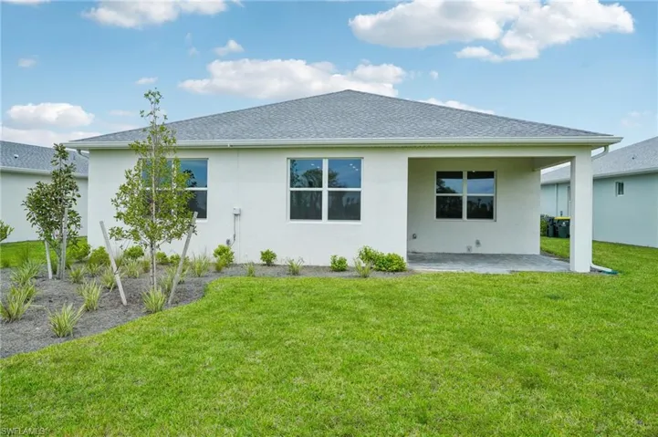 Rear view of property featuring a lawn and a patio
