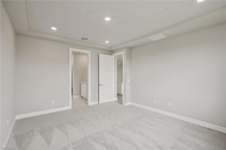 Unfurnished bedroom with light colored carpet and ensuite bathroom