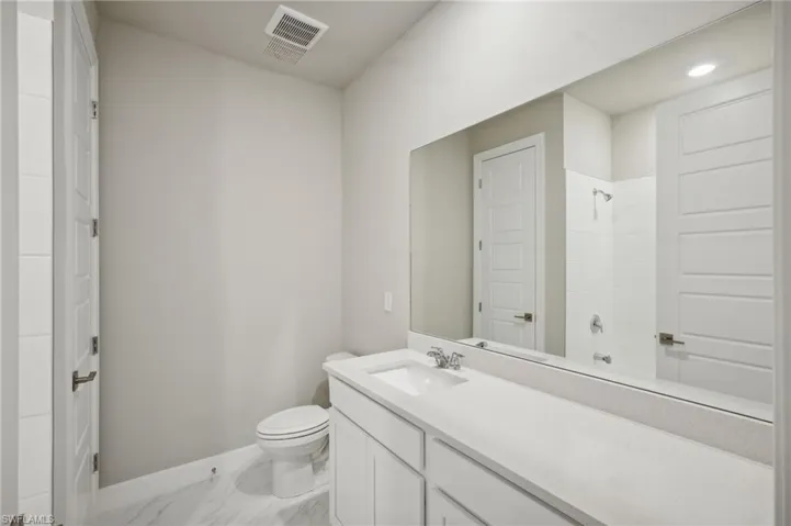 Bathroom featuring walk in shower, vanity, and toilet