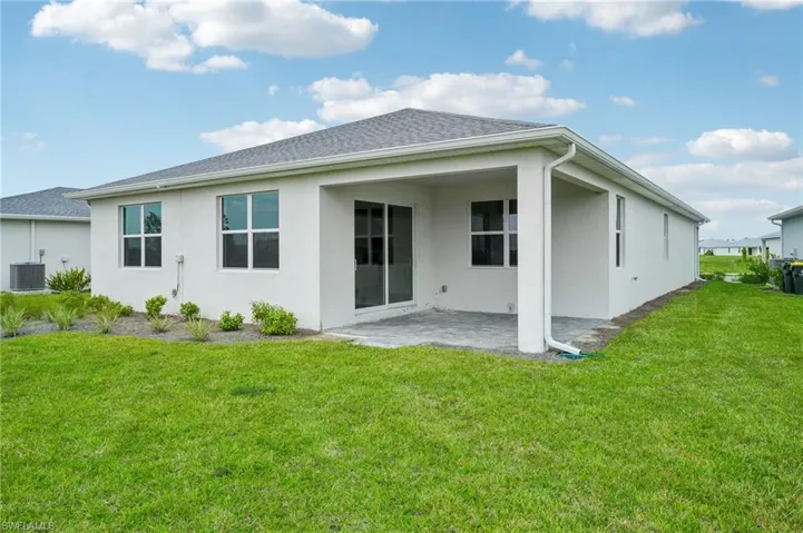 Rear view of house featuring central AC unit, a yard, and a patio