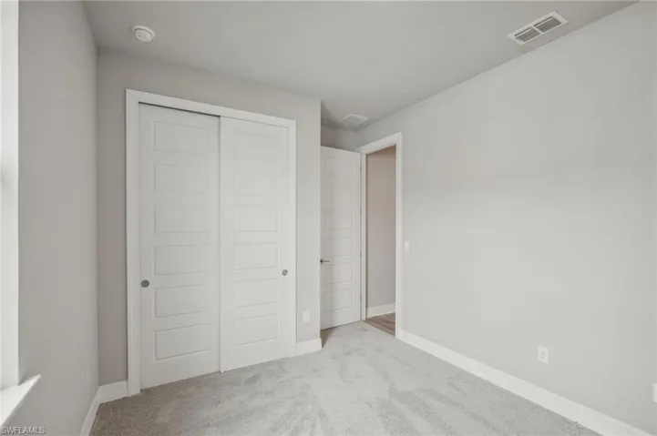 Unfurnished bedroom with light carpet and a closet