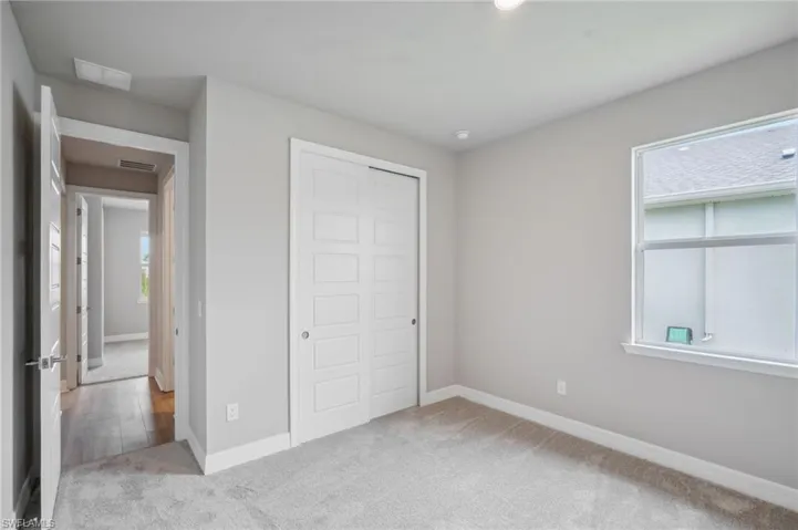 Unfurnished bedroom with light colored carpet, a closet, and multiple windows