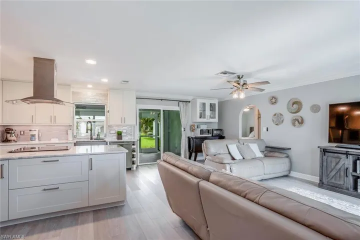 Living area with light wood-type flooring, crown molding, and ceiling fan