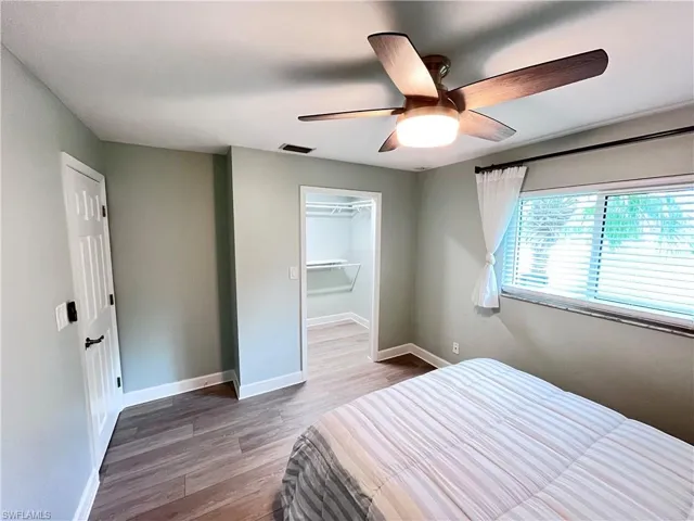 Bedroom with wood finished floors, a ceiling fan, and a walk in closet