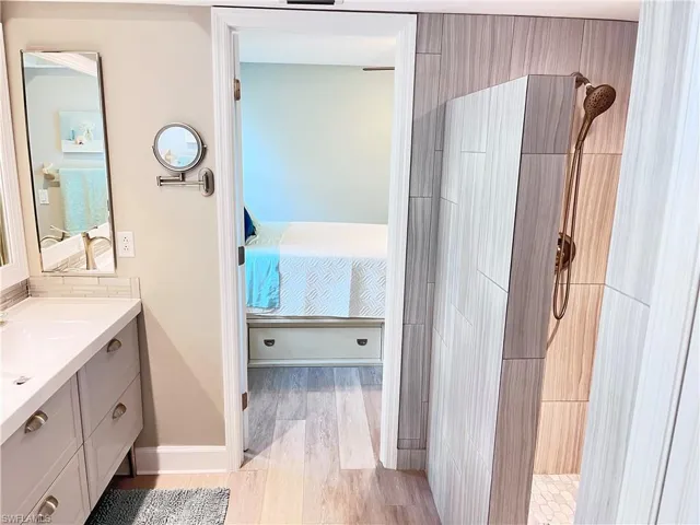 Bathroom featuring tiled shower, vanity, wood finished floors, and ensuite bathroom