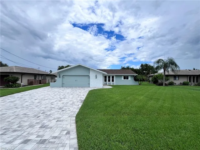 Ranch-style house featuring a garage, decorative driveway, a front yard, and stucco siding