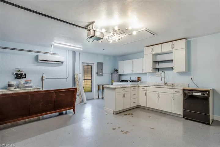 Kitchen with open shelves, white cabinetry, black dishwasher, light countertops, and a chandelier