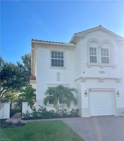 Mediterranean / spanish home featuring stucco siding, an attached garage, a gate, driveway, and a front lawn