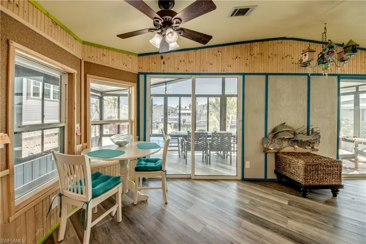 Sunroom / solarium with ornamental molding, wood finished floors, vaulted ceiling, and wood walls