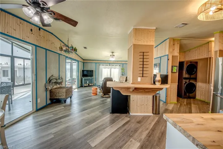 Kitchen featuring wooden counters, lofted ceiling, freestanding refrigerator, wood finished floors, and stacked washer / dryer