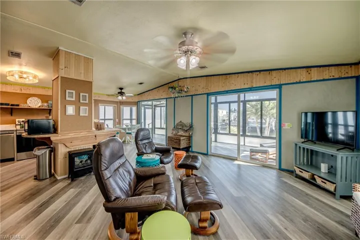 Living area featuring vaulted ceiling, light wood finished floors, and ceiling fan