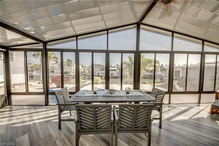 Sunroom / solarium featuring a water view, a wall of windows, vaulted ceiling, healthy amount of natural light, and wood finished floors