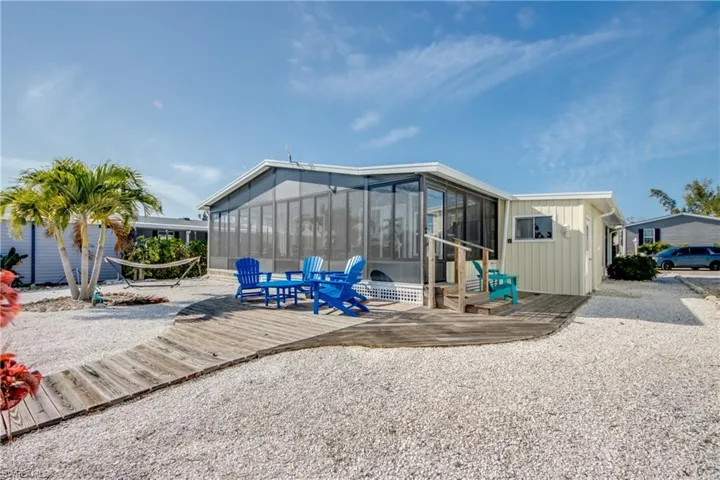 Rear view of property featuring a wooden deck, a sunroom, board and batten siding, and a patio area
