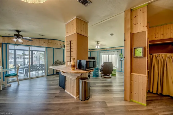 Kitchen featuring wood counters, ceiling fan, dark wood-style flooring, wood walls, and healthy amount of natural light