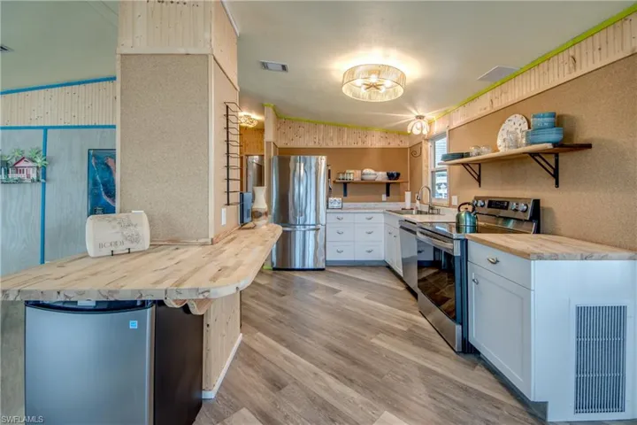 Kitchen featuring wood counters, appliances with stainless steel finishes, light wood finished floors, white cabinetry, and open shelves