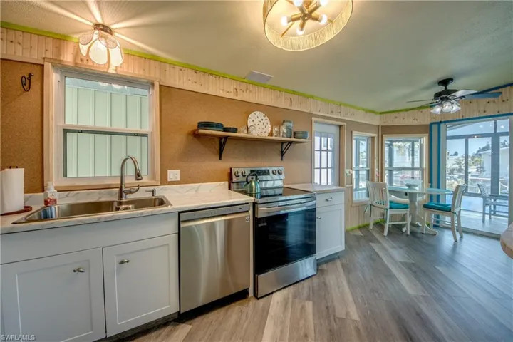 Kitchen featuring appliances with stainless steel finishes, white cabinetry, light countertops, and open shelves