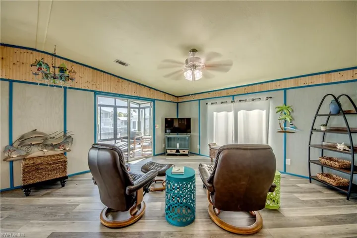 Living area with lofted ceiling, wood finished floors, a ceiling fan, and wooden walls