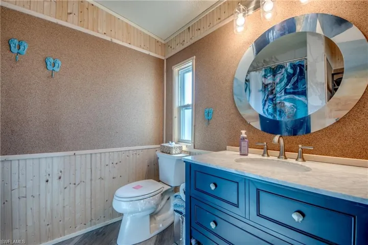 Bathroom with wood walls, a wainscoted wall, vanity, a shower with shower curtain, and dark wood-style flooring