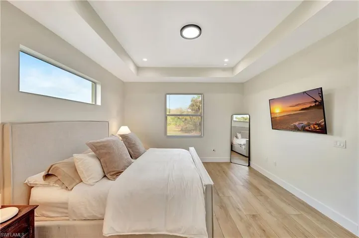 Bedroom with a tray ceiling and light wood-type flooring