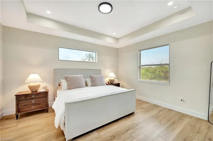 Bedroom with light hardwood / wood-style floors and a raised ceiling