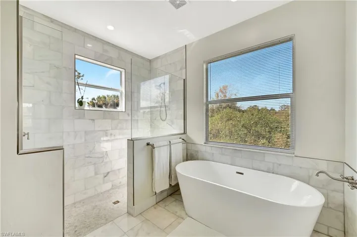 Bathroom featuring marble walls and independent shower and bath