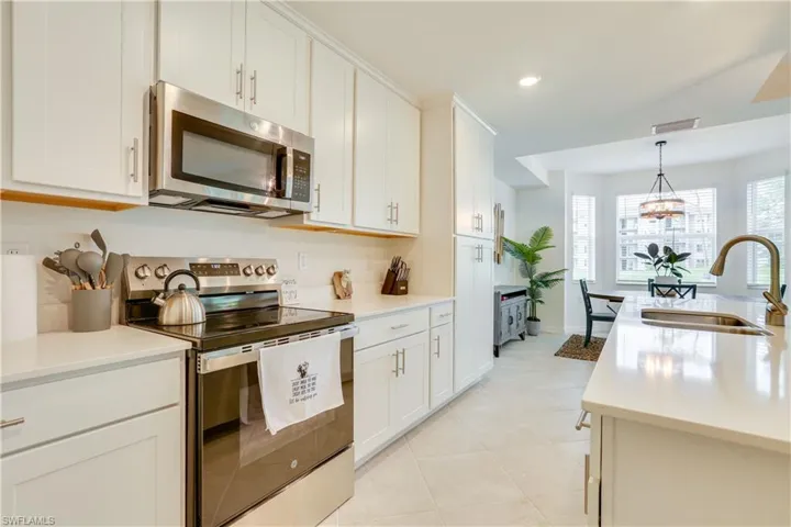 Kitchen featuring stainless steel appliances, pendant lighting, white cabinets, light stone countertops, and recessed lighting