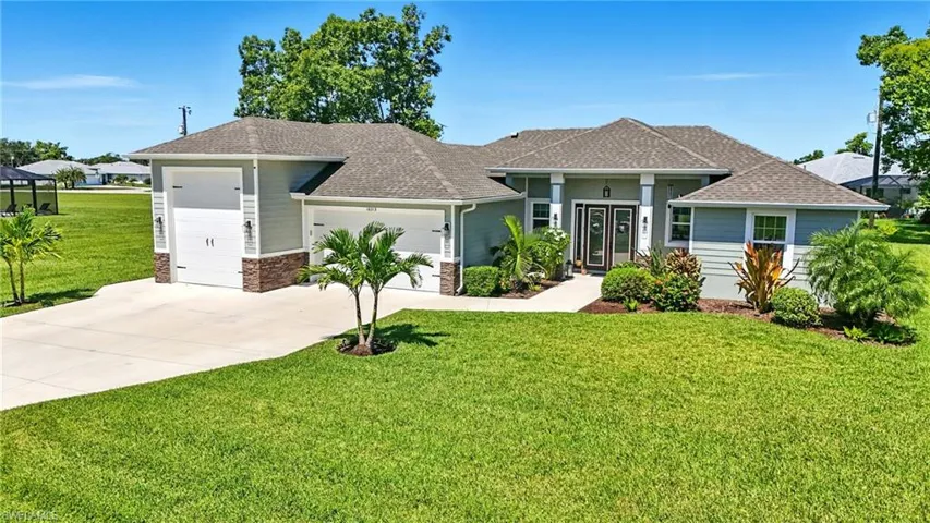 View of front of house with a shingled roof, a front yard, an attached garage, concrete driveway, and stone siding