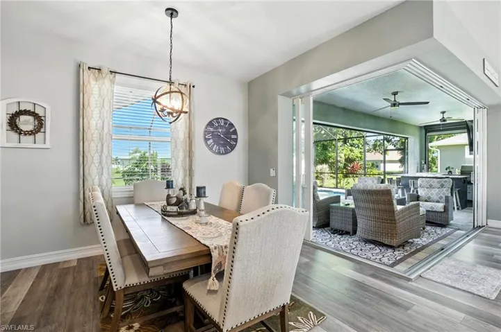 Dining area featuring a sunroom, wood finished floors, a ceiling fan, and a chandelier