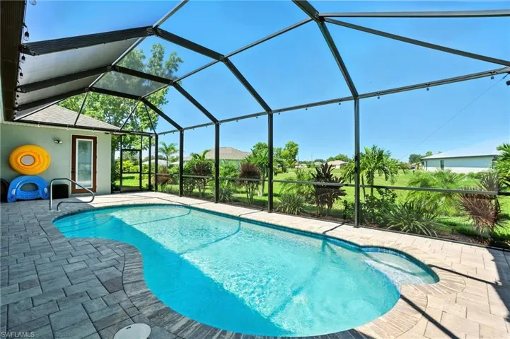 Swimming pool featuring a sunroom, a patio area, and glass enclosure