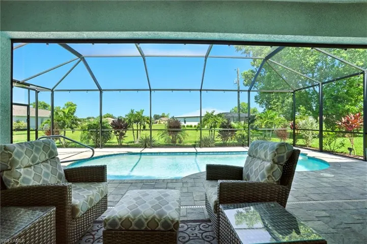Outdoor pool with a sunroom, a patio area, and glass enclosure