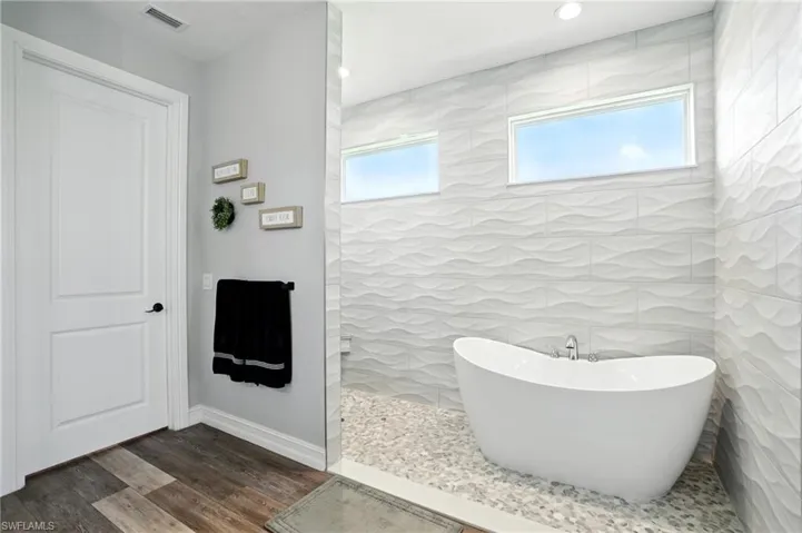 Full bath with a freestanding tub, walk in shower, dark wood finished floors, and recessed lighting