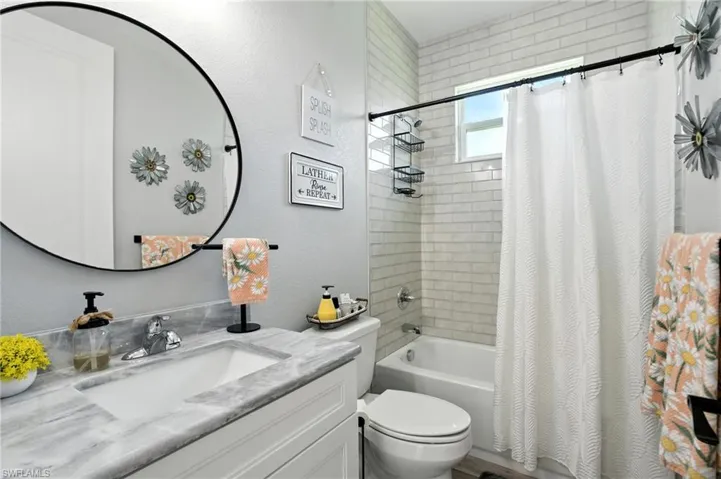 Full bath with shower / bath combo, vanity, and a textured wall