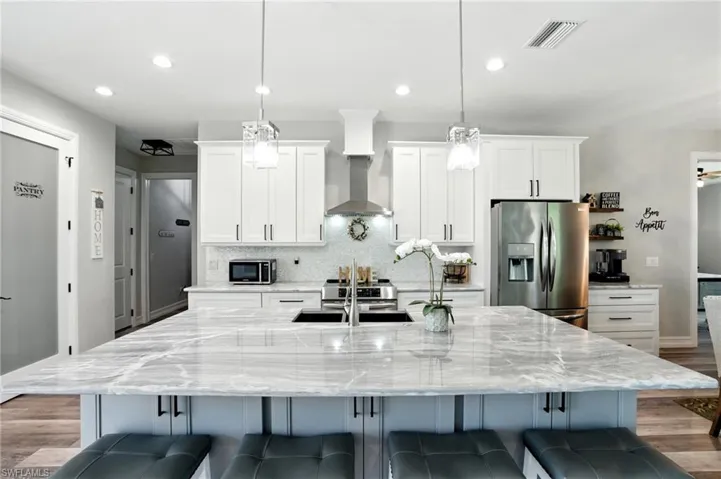 Kitchen featuring light wood-style flooring, white cabinets, stainless steel fridge, tasteful backsplash, and recessed lighting
