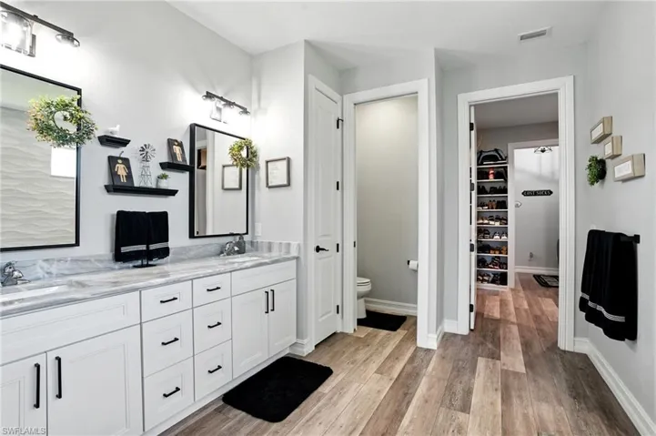 Bathroom with double vanity, light wood-style flooring, and a spacious closet